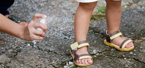 Mother applying mosquito repellent spray for baby protection outdoors