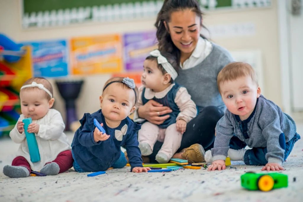 Toddlers with caregiver in Canadian daycare setting showing proper supervision