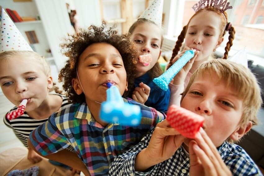 Happy kids blowing party horns at a birthday celebration in Canada